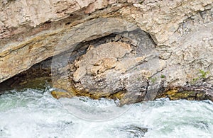 Boulder river rushing through a sea grotto and jagged rock wall in Montana photo