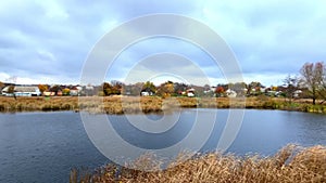 Scenic calm panorama on lake,pond,river with water in countryside rural village area with private houses, nature suburb landscape