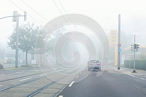 Scenic city road street jam with many cars at foggy misty rainy haze morning low poor visibility cold spring autumn