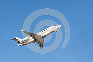 Scenic close bottom view modern luxury expensive white private jet plane dispatching from airport isolated on blue clear