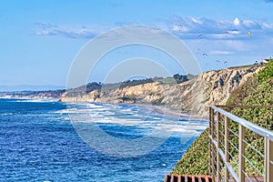 Scenic coast and sea of San Diego California with parachuters against blue sky