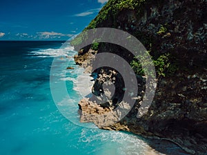 Scenic coastline with rocks and blue ocean with waves in Bali. Aerial view