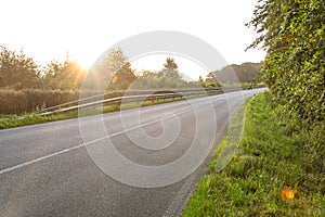Scenic country road at sunrise with lens flare