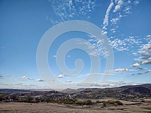 Scenic countryside landscape with rolling hills, clear blue sky, and scattered clouds