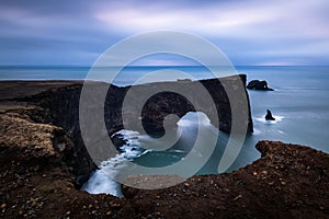 Scenic Dyrholaey rock formation at stormy cloudy morning on cold atlantic coast in iceland