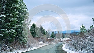 Scenic early spring view with snowy dirt road through the pass, green larch trees, snow and forest on the slopes against