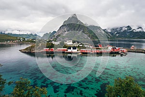 Scenic fjord on Lofoten islands with typical red fishing hut and towering mountain peaks
