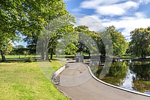 Scenic footpath with benches around a small shallow pond in Duthie Park, Aberdeen