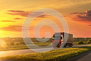 Scenic front view big long heavy semi-treailer truck with sea shipping container driving highway dramatic warm morning