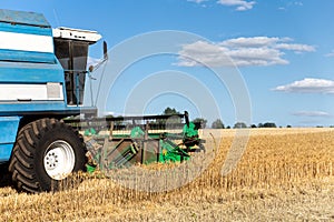 Scenic front view Big powerful industrial combine harvester machine reaping golden ripe wheat cereal field on bright