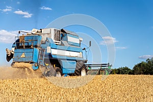 Scenic front view Big powerful industrial combine harvester machine reaping golden ripe wheat cereal field on bright