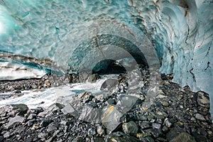 Scenic glacier ice caves with river flowing out from inside