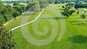 Scenic Golf Course Aerial Perspective, Lush green golf course with golfers and pathways under clear skies.