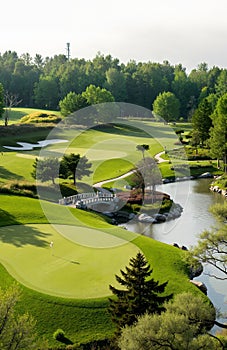 A scenic golf course with a bridge over a river surrounded by trees