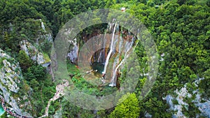 Scenic high waterfall cascading over lush green cliff in dense forest. Mountain stream with clear water.