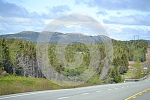 Scenic hilly landscape along Newfoundland highway with cloud filled sky