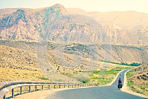 Scenic landscape back view of male cyclist solo touring in tranquil countryside fully loaded with bags outdoors in summer heat.