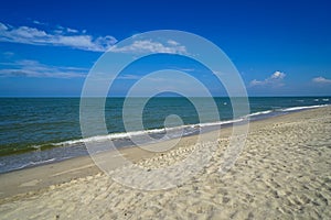 Scenic landscape of calm sea wave on white sandy beach with white cloud and blue sky background