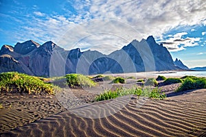 Scenic landscape with most breathtaking mountains Vestrahorn on the Stokksnes peninsula and cozy lagoon with green grass on the