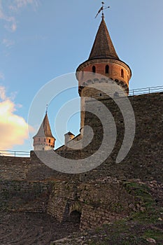 Scenic landscape photo of ancient Kamianets-Podilskyi Castle. High and thick stone walls with towers against blue sky