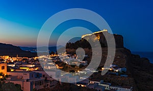 Scenic landscape photo of night Lindos town and castle on Rhodes island, Dodecanese, Greece. Panorama with bright lights,