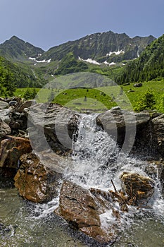 Scenic landscape of snowy mountain in the background and a small waterfall in the foreground