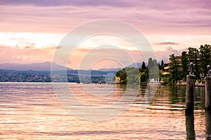 Scenic landscape of sunset with dramatic pink sky and reflection in water on Garda lake in Sirmione, Lombardy, Italy. Beautiful