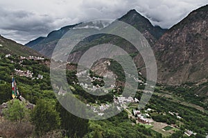 Scenic landscape of traditional tibetan village against mountains and dramatic cloudy sky