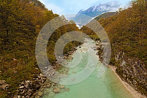 Scenic landscape view of alpine Soca River. Emerald green water flows between mountains with dense forest