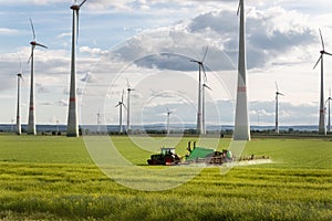 Scenic landscape view big modern tractor machine with sprayer equipment spraying fertilizer in rapeseed agricultural