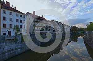 Scenic landscape view of Ljubljana. Embankment of Ljubljanica River with ancient colorful buildings against blue sky