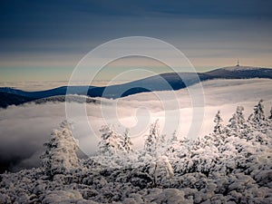 Scenic landscape with a view from a mounatin range to the valley filled with low clouds and fog during temperature inversion