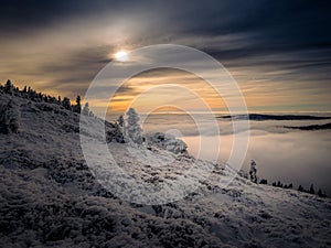 Scenic landscape with a view from a mounatin range to the valley filled with low clouds and fog during temperature inversion