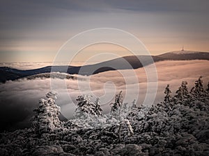 Scenic landscape with a view from a mounatin range to the valley filled with low clouds and fog during temperature inversion