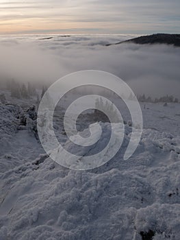 Scenic landscape with a view from a mounatin range to the valley filled with low clouds and fog during temperature inversion