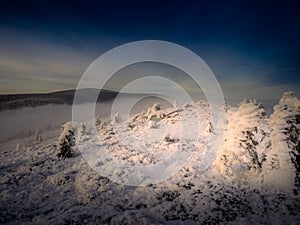 Scenic landscape with a view from a mounatin range to the valley filled with low clouds and fog during temperature inversion