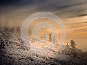 Scenic landscape with a view from a mounatin range to the valley filled with low clouds and fog during temperature inversion