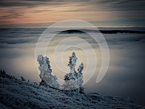 Scenic landscape with a view from a mounatin range to the valley filled with low clouds and fog during temperature inversion