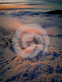 Scenic landscape with a view from a mounatin range to the valley filled with low clouds and fog during temperature inversion