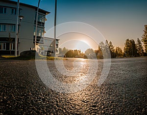 Scenic low level view on rising Sun over empty parking lot close to typical office building, early morning, clear sky with Sunrise