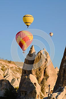 Scenic morning landscape view of flying hot air balloons over amazing cave houses in shaped sandstone rocks near Goreme