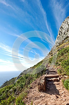 Scenic mountain hiking trail with copy space, rough rocks or stones leading to beautiful view of ocean or sea from the