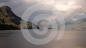 Scenic mountainous view on the shore of the clear Pitt lake on a foggy day