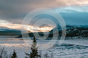 Scenic panorama of Sunset over frozen Ume river with first ice, mountains covered by clouds. Lapland Sweden. Somewhere around
