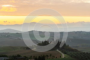 Scenic panorama of the Tuscan landscape with hills and harvest fields in golden morning light, Val d'Orcia, Italy.