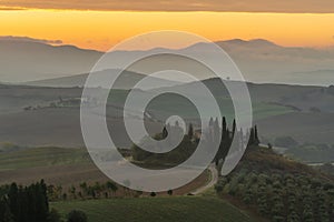 Scenic panorama of the Tuscan landscape with hills and harvest fields in golden morning light, Val d'Orcia, Italy.