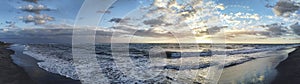 Scenic panoramic sunset at the sea in golden hour with awe cloudy sky in a cold winter day in the Roman coast. Italy