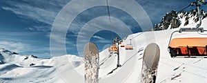 Scenic panoramic view of alpine peaks with ski lift ropeway on hilghland mountain winter resort and snow making machines on bright