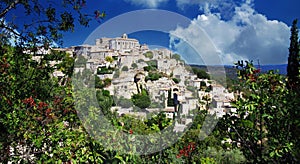 Scenic panoramic view on medieval picturesque old french village on hill top, blue summer sky, fluffy clouds - Gordes, Provence,