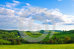 Scenic panoramic view of rolling countryside green farm fields with sheep, cow and green grass